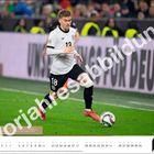 "Vorratsabbildung." Ein Fußballspieler in weißem Trikot mit der Nummer 13 läuft mit einem Ball auf einem grünen Spielfeld. Oktober-Kalender.