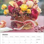 "Oktober" steht über einem Kalender. Ein Blumengesteck mit roten und gelben Rosen dominiert die Darstellung.