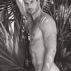 Kalender mit der Zahl 10. Ein muskulöser Mann steht zwischen Palmblättern und schaut ernst. Schwarzweißaufnahme.