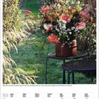 Oktoberkalender mit Blumenarrangement auf Tisch im Garten. Bunte herbstliche Blumen vor grünem Hintergrund.