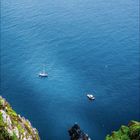 Kalenderblatt für Oktober 2021. Ein steiler grüner Abhang führt zu einem blauen Meer mit Booten und einer fernen Insel.