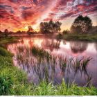 10, 2021. Ein malerischer Sonnenuntergang über einem Fluss mit üppigem Uferbewuchs und dramatischem Himmel.