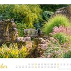 "Oktober" und Kalendarium. Eine Holzbank steht zwischen Ruinen und üppigem grünen Laub in einem idyllischen Garten.