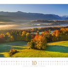 Kalenderseite: Oktober. Herbstliche Landschaft mit bunten Bäumen, grüne Wiesen, Berge im Hintergrund, Nebel.