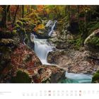 "Oktober, Montag der 10." Kalenderblatt mit Naturfoto: Ein Wasserfall fließt durch eine herbstlich bunte Waldlandschaft.
