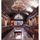 09 März. Ein prunkvoller Lesesaal mit opulentem Kronleuchter und hohen Bücherregalen.