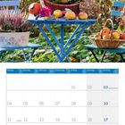 Kalenderblatt für Oktober 2027. Blauer Tisch mit Korb voller bunter Blumen und Äpfel in einem herbstlichen Garten.