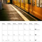 Kalendarium mit Oktober 2027. Foto von U-Bahn mit gelbem Zug, Uhr, und Anzeigetafel in einem Bahnhof.