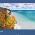 "Oktober 2027". Küstenlinie mit gelben und orangenen Herbstbäumen, blauer Himmel und Wasser.