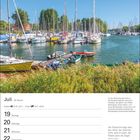 Juli, Woche 29, Krebs 21.6–22.7, Löwe 23.7–22.8. Ein Hafen mit vielen Segelbooten und grünem Ufer im Hintergrund.