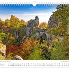Oktoberkalenderblatt zeigt die Basteibrücke in der Sächsischen Schweiz im Herbst, umgeben von bunten Blättern.