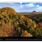 Oktober. Kalenderseite mit herbstlicher Waldlandschaft, leuchtende Bäume und blauer Himmel.