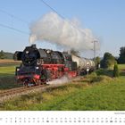 Kalenderblatt für Oktober zeigt Lokomotive der Baureihe 50. Dampflokomotive fährt durch grüne Landschaft.