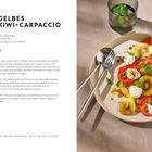 Text: Gelbes Kiwi-Carpaccio Rezept. Zutaten: gelbe Kiwis, Strauchtomaten, Büffelmozzarella, Basilikum. Bild: Teller mit buntem Salat.