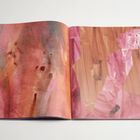 Ein aufgeschlagenes Buch mit abstrakten rosa und orangen Farbmischungen auf beiden Seiten.