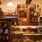 Ein Schild mit der Aufschrift "Ooh coso! Voi dove siete? La su dalla ai tordi!" in einem rustikalen Delikatessenladen.