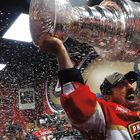 "Panthers" auf einem Jersey. Jemand hebt einen großen Pokal, während im Hintergrund Konfetti regnet. Feierliche Szene.