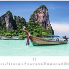 Phuket, Thailand. Ein traditionelles Boot auf türkisfarbenem Wasser, im Hintergrund grüne Klippen und blauer Himmel.