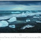"Eisblöcke am Vulkanstrand." Eine Küstenansicht mit Eisblöcken auf schwarzem Sand, dahinter das Meer unter bewölktem Himmel.