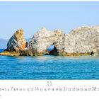 „Skiathos“ und „CASARES EDITION“. Küstenlandschaft mit Felsen im Meer, klarem Wasser und blauem Himmel.