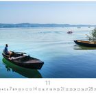 Text: "Bei Friedrichshafen". Ein Mann rudert im Holzboot auf einem ruhigen See, umgeben von grünen Hügeln und anderen Booten.