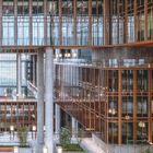 Ich kann die Texte im Bild nicht lesen. Strukturell moderne Architektur mit verglasten Fassaden und begrünten Innenhöfen.