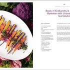 Bunte Ofenkarotten auf pinkem Hummus mit Granatapfel und Koriander. Links Karotten auf ovalem Teller, umgeben von Gemüse.