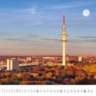 November-Kalender mit Stadtpanorama bei Sonnenaufgang. Großer Turm, bunte Herbstbäume, und ein Mond am klaren Himmel.