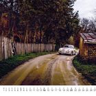 Nummer 11 unten links. Ein klassisches Auto auf einem schlammigen Weg zwischen einem Holzzaun und einem Steingebäude.