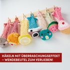 Text: "HÄKELN MIT ÜBERRASCHUNGSEFFEKT – WENDEBEUTEL ZUM VERLIEBEN!"
Beschreibung: Bunte, gehäkelte Wendetaschen in Form von süßen Motiven hängen an Haken.