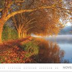 "NOVEMBER" steht groß geschrieben. Rechts unten ein Kalender. Orange Herbstbäume spiegeln sich im ruhigen See.