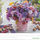 November-Kalenderblatt mit lilafarbenen Blumen und roten Beeren in einem gepunkteten Eimer.