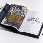 "Yokai Monster in Werken der japanischen Holzschnittkunst." Buchseite mit farbenfroher Illustration von Figuren.