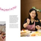 Zwei Frauen genießen gemeinsam GALBI JJIM. Links ein Bild von GALBI JJIM in einer Schüssel. Rosa Blumendekoration oben.