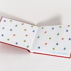 Geöffnetes Buch mit weißen Seiten, bedruckt mit vielen kleinen bunten Blumenmustern in Grün, Blau und Orange.