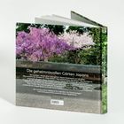 Rückseite eines Buches mit dem Titel "Die geheimnisvollen Gärten Japans", blühende Bäume und Kies im Hintergrund.