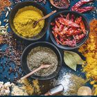 11, Tage 1 bis 30. Gewürze in schwarzen Schalen, rote Chilis, gelbes und grünes Pulver, Lorbeerblätter und Pfeffer.