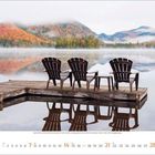 Kalenderseite: November 2023. Drei Stühle auf einem Steg spiegeln sich in einem ruhigen See, umgeben von herbstlichen Bergen.