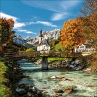 Eine verschneite Berglandschaft mit Tannenbäumen im Vordergrund und steilen, bewaldeten Berghängen im Hintergrund.