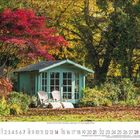 Kalender mit Novemberdaten. Gartenhaus zwischen Bäumen, zwei weiße Stühle davor, rot und gelb gefärbtes Laub im Herbst.