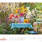 November: Ein Tisch mit blau-weißem Tuch, Kürbissen und Blumen in einem Garten. Kalenderdaten darunter.
