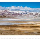 November 2023 Kalender. Weite Landschaft mit schneebedeckten Bergen und sandfarbenen Ebenen, blauer Himmel.