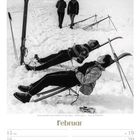 "Februar; Sonne genießen beim Skifahren in den Alpen - 1950er Jahre; Zwei Personen liegen entspannt im Schnee an Skiern."