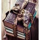 10. März, Stapel alter Bücher mit einem Band. Ein Stapel Bücher, verziert mit einem goldgemusterten Band und Kristallen.