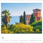 11; Botanischer Garten Hanbury, Italien. Ein rotes Gebäude vor blauem Meer, umgeben von grünen Bäumen und Palmen.