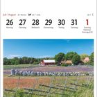 Juli | August, 30. Woche. Schiffsetzung bei Gannarve auf Gotland. Bunte Wiese mit Haus, Holzzaun, Steinen und Bäumen.