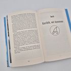 Text "Teil 6 Karibik, wir kommen". Illustration eines Hais. Buch aufgeschlagen mit fortlaufendem Text auf der linken Seite.