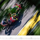 November, GP Deutschland (Sachsenring). Ein Fahrer auf einem rot-grünen Motorrad in schneller Bewegung auf einer Rennstrecke.