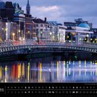 Die Ha'penny Bridge über den Fluss Liffey in Dublin. Abendbeleuchtung und Spiegelungen im Wasser. Gebäude im Hintergrund.