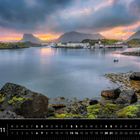 Lofoten 11. Kalenderansicht mit Küstenlandschaft, Bergen, Wasser, Steinen und bewölktem Himmel bei Sonnenuntergang.